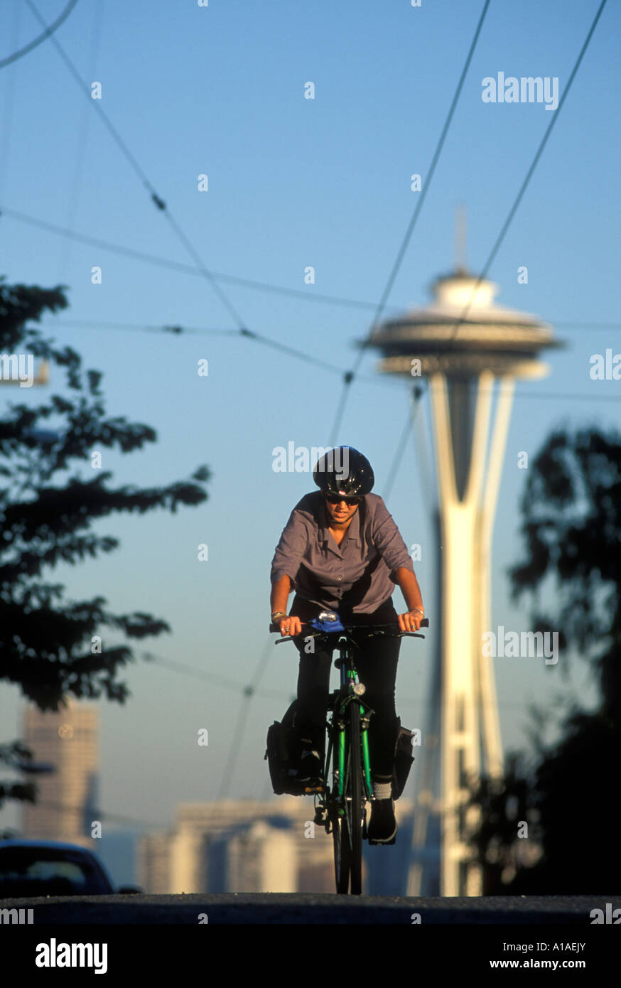 Stati Uniti Washington Seattle la donna corse in mountain bike fino Queen Anne Hill con lo Space Needle in background Foto Stock