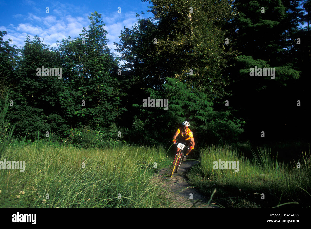 Stati Uniti Washington Seattle Mountain bike rider gare attraverso l'erba alta in Des Moines Creek Park vicino al Sea Tac Airport Foto Stock