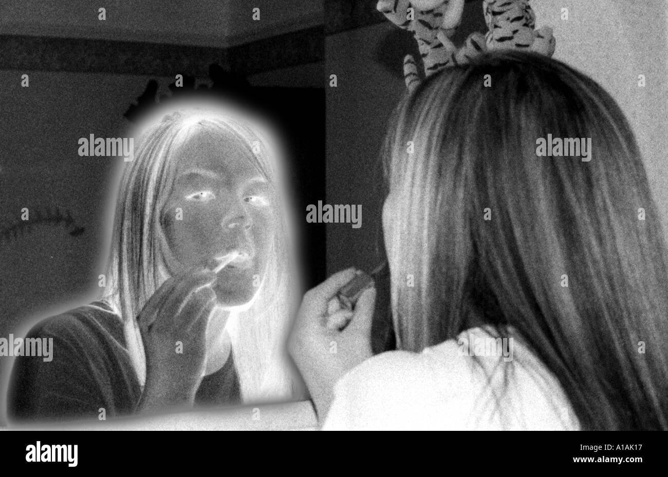 Immagine in bianco e nero di una giovane donna il rossetto in uno specchio di riflessione in un'immagine in negativo Foto Stock