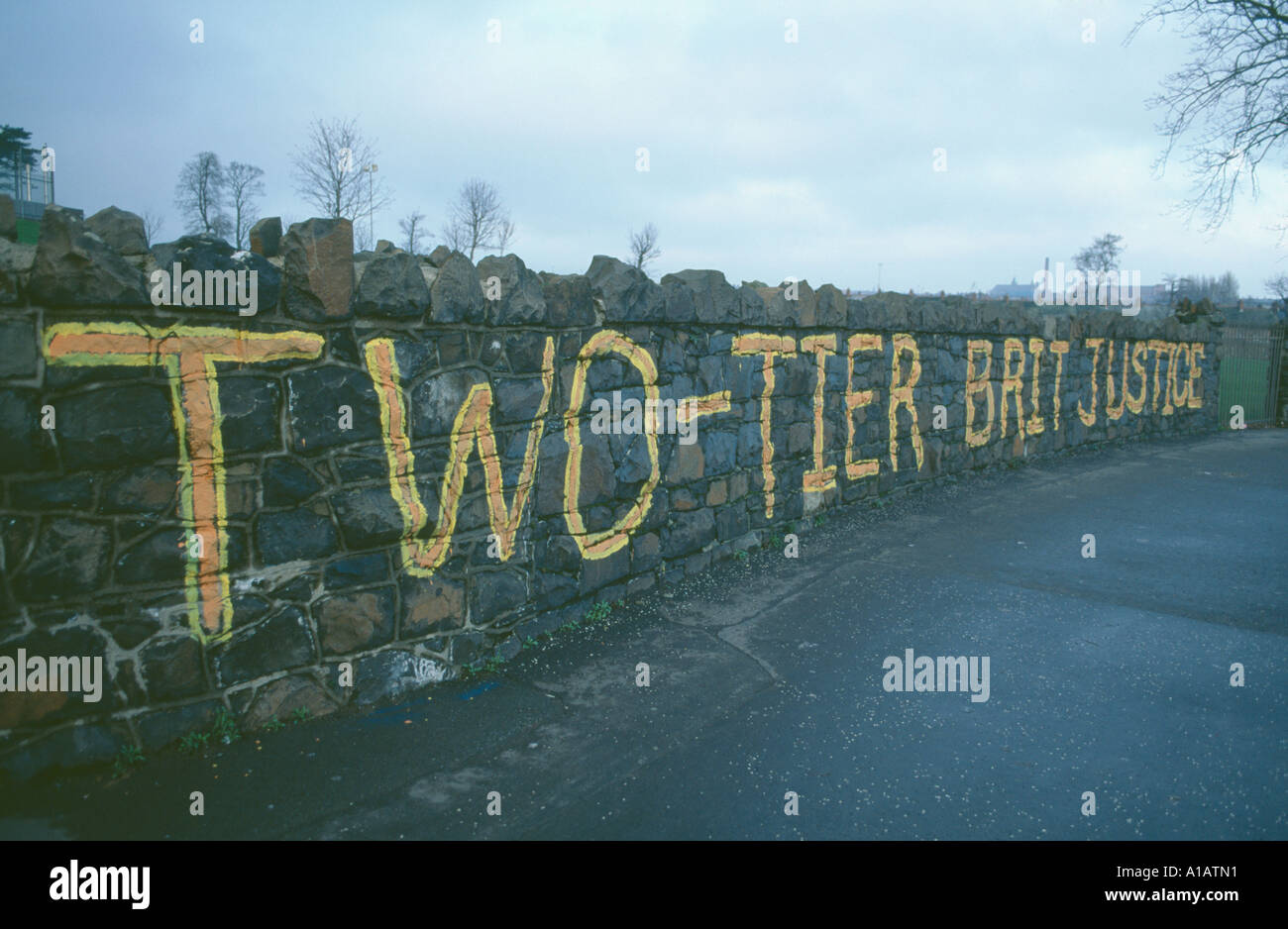 Irlanda, Nord, Belfast, Falls Road, zona di Beechmount, anti-innesti britannici su un muro di pietra che dice "Brit Justice a due livelli". Foto Stock