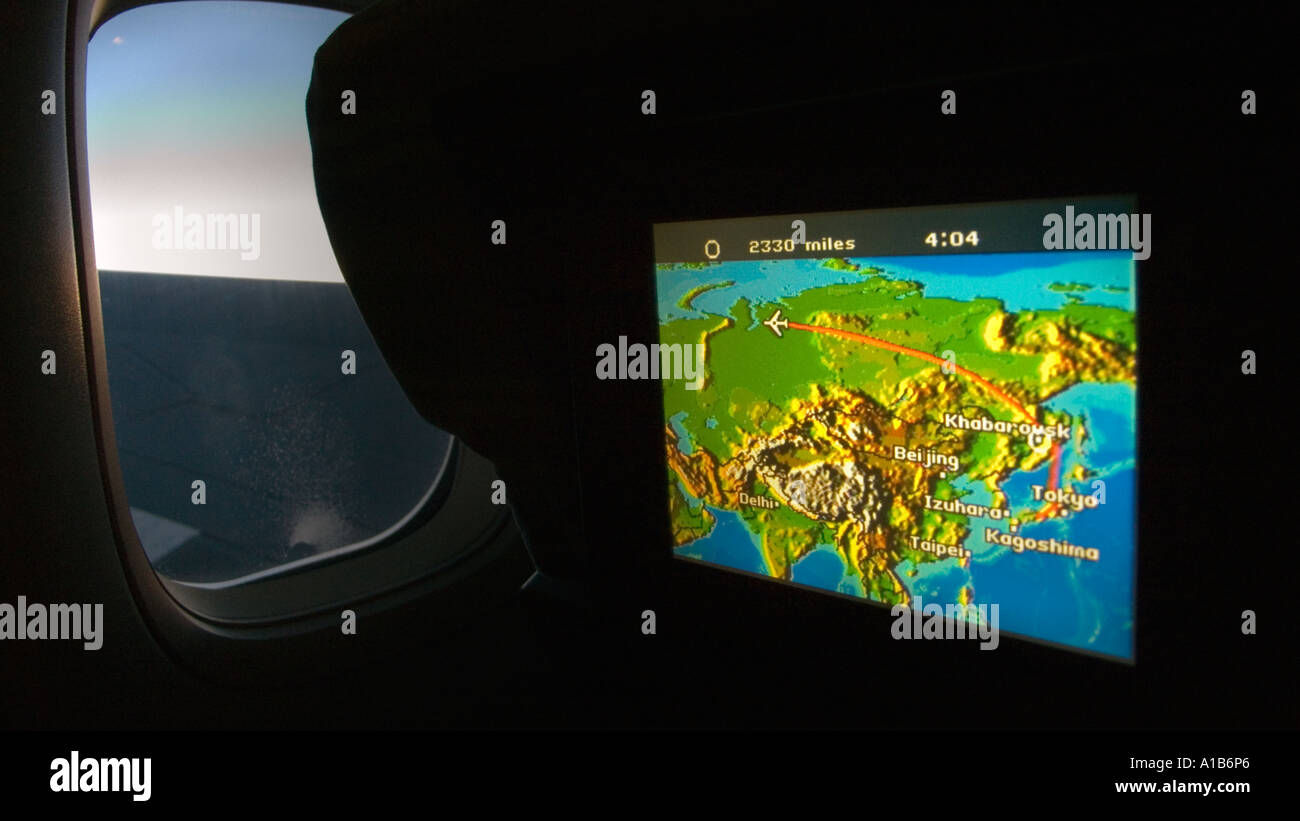Monitor del sedile che mostra mappa di Eurasia e volo in rotta dal Giappone oscurato cabina con finestra e vista del Boeing 747 Ala Foto Stock