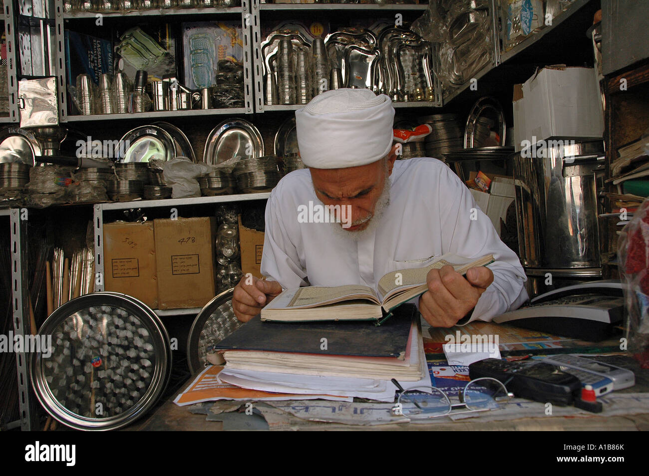 Negoziante la lettura del testo sacro dell'Islam Corano in Khan el-Khalili un grande souk nel centro storico del Cairo islamico Egitto Foto Stock