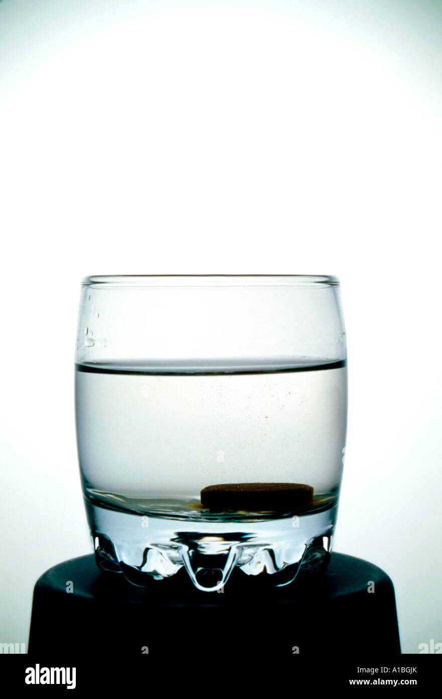 Bicchiere di acqua su un fondo bianco con pasticche effervescenti Foto Stock