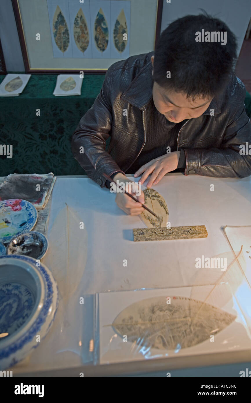 Cina CHONGQUING artista cinese utilizzando inchiostro e spazzola per dipingere scene tradizionali su foglie Foto Stock
