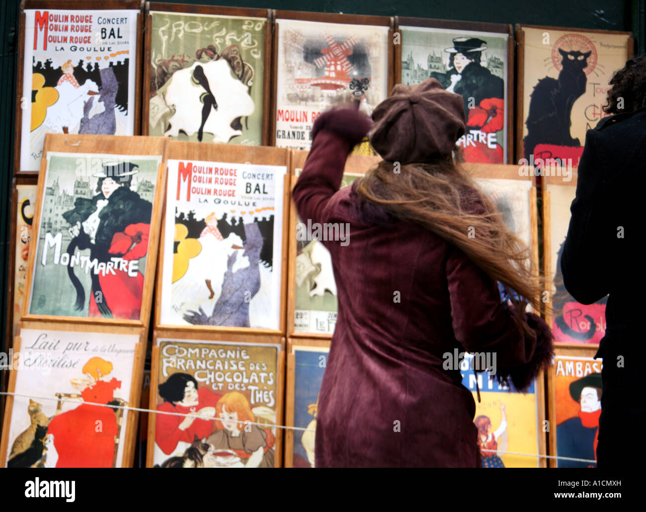 Donna guarda al display poster a Montmartre a Parigi Foto Stock