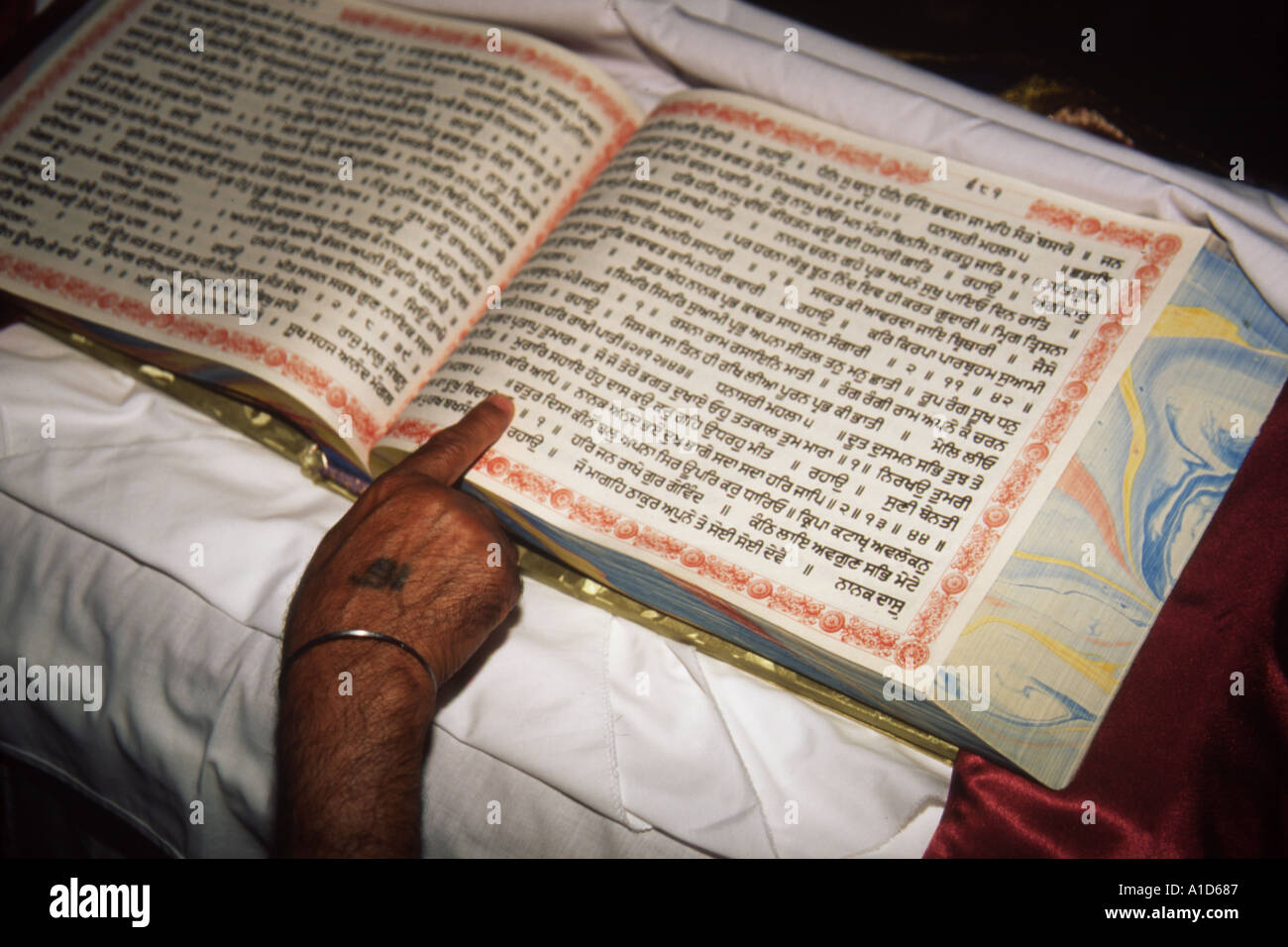 I testi sacri Guru Granth Sahib sono scritti in gurmaki script. Qui un granthi sceglie una lettera a caso per il nome di un nuovo bambino. Foto Stock