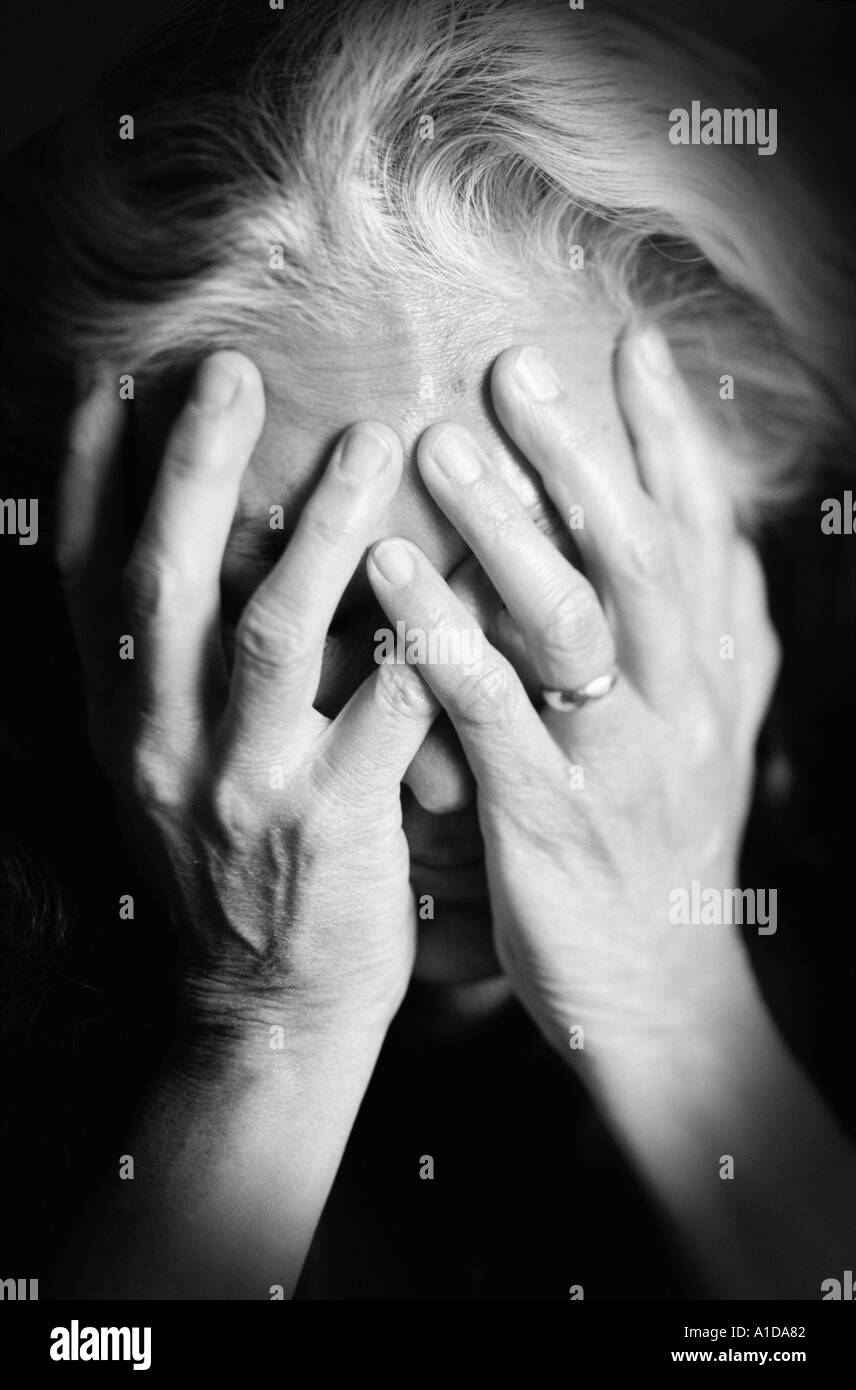 Donna anziana con le mani al viso Foto Stock