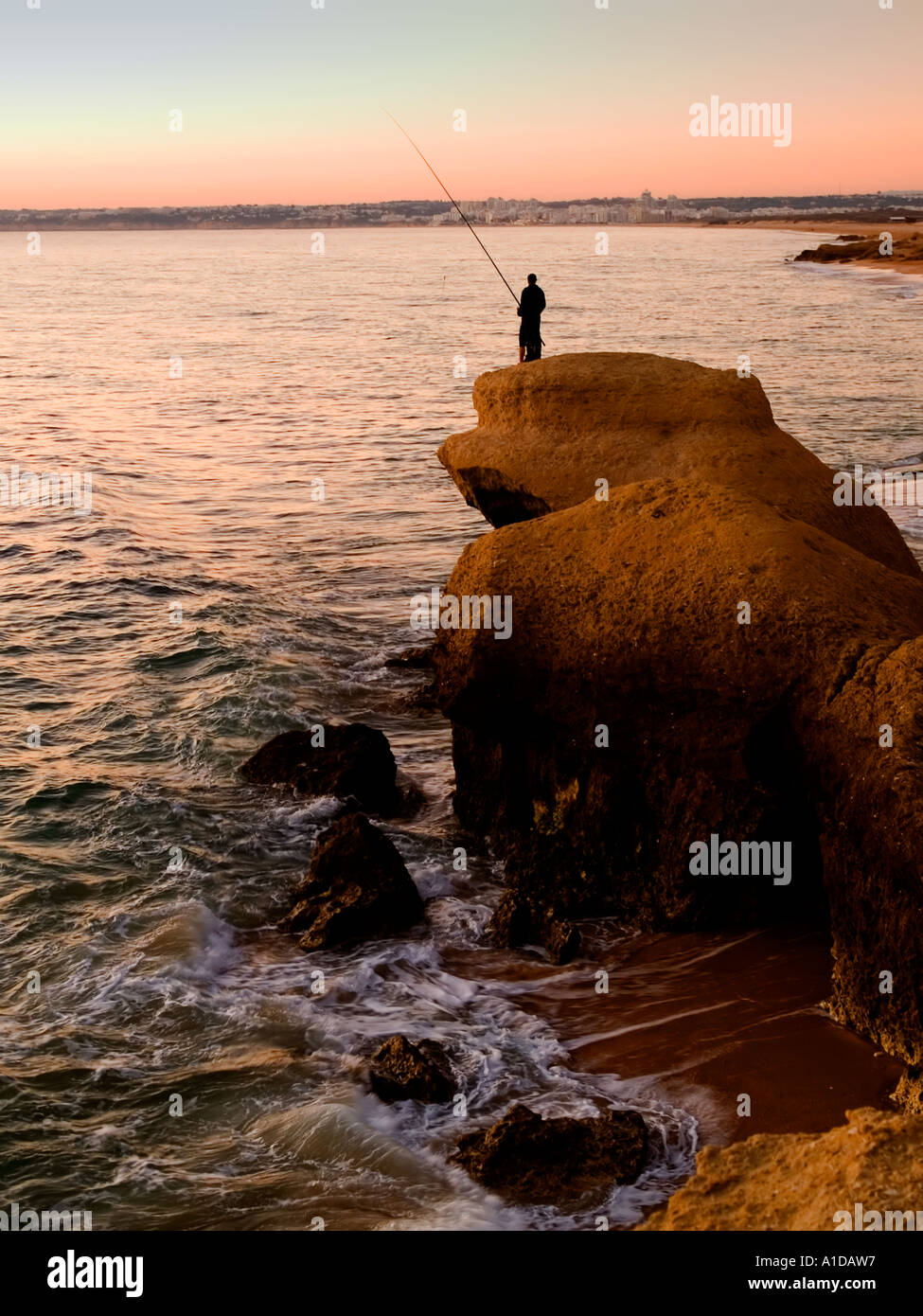 La pesca con lenza in mare nel tramonto a spiaggia di Galé circa 7 km ad ovest di Albufeira Algarve Portogallo Foto Stock
