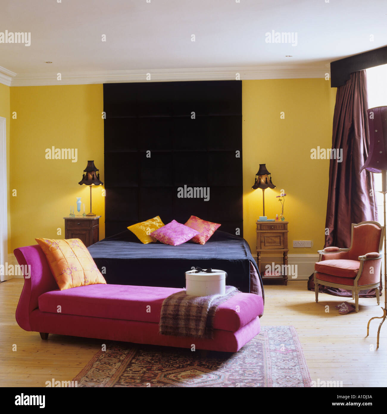 Rosa chaise longue e nero letto matrimoniale in camera da letto giallo Foto Stock