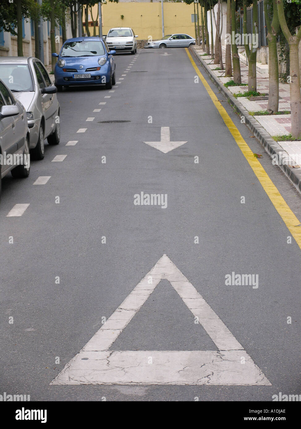 Strada con parcheggio non linea gialla un lato parcheggio altro lato un modo freccia direzionale e il simbolo di arresto Foto Stock