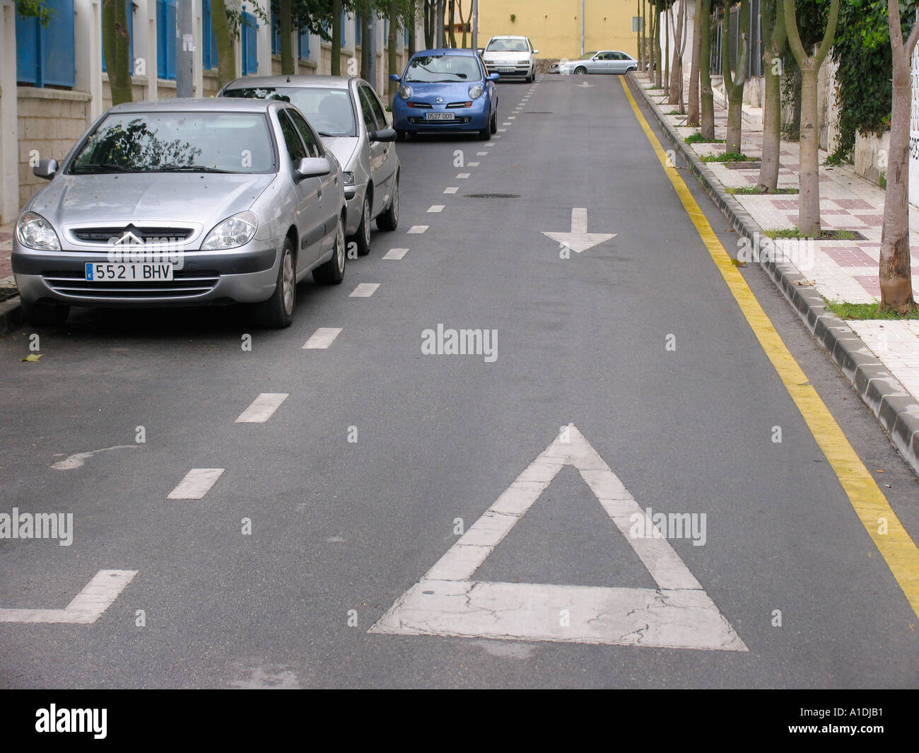 Strada con parcheggio non linea gialla un lato parcheggio altro lato un modo freccia direzionale e il simbolo di arresto Foto Stock