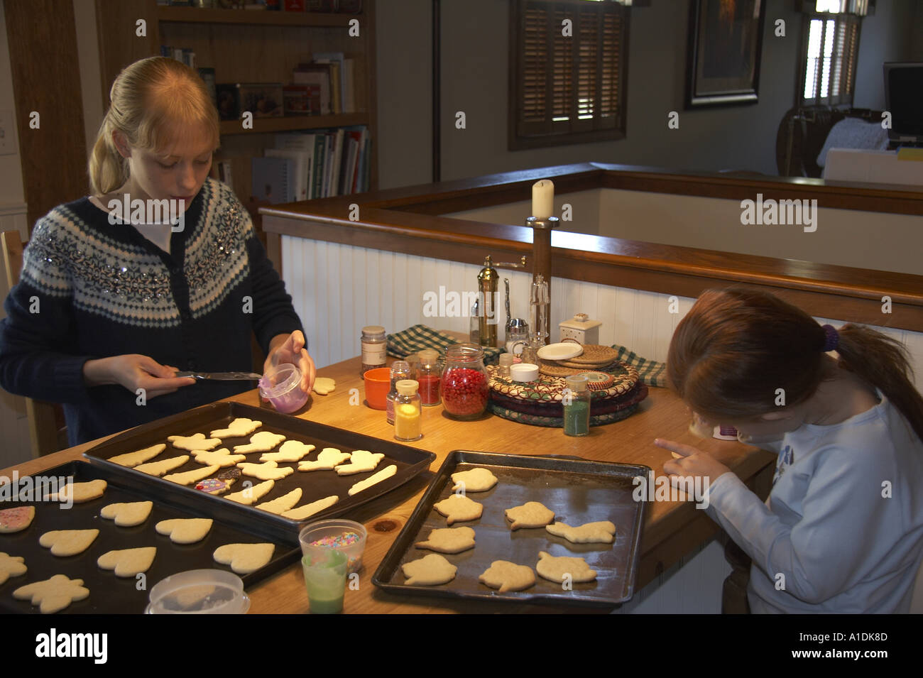 Le ragazze la decorazione di biscotti di zucchero al tavolo della cucina Foto Stock