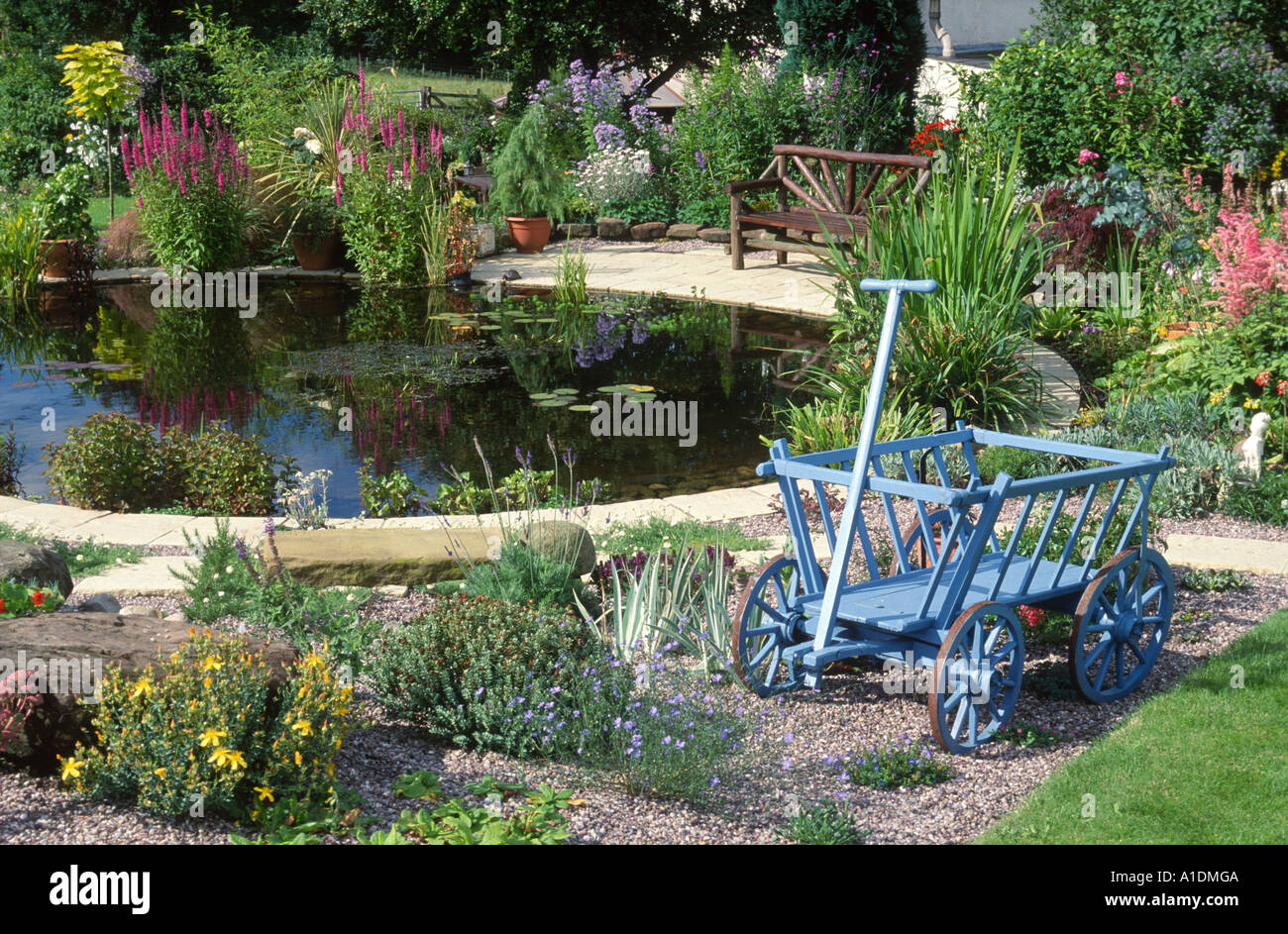 Grande piscina circolare con pavimentazione e vecchi camion in giardino cottage Foto Stock