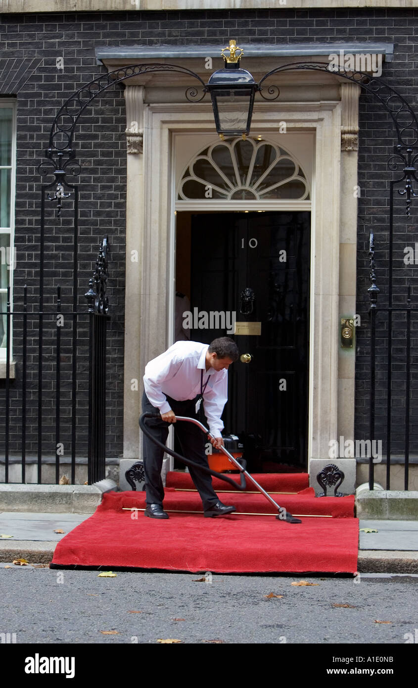 Il detergente hoovers il tappeto al di fuori del numero 10 di Downing Street la casa del Primo Ministro britannico London Regno Unito Foto Stock