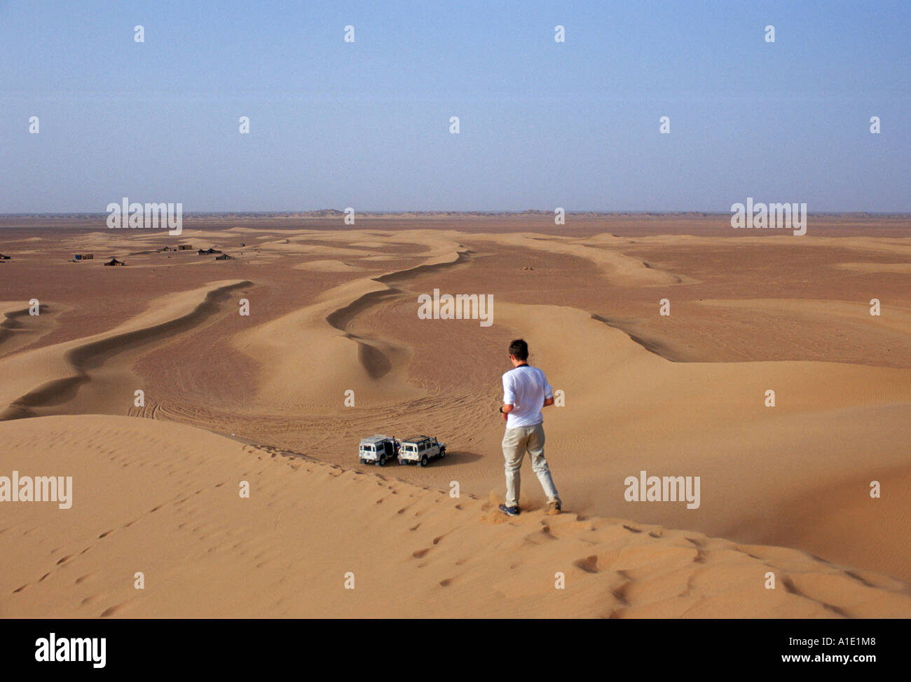 Giovane uomo cammina per le dune di sabbia nel deserto del Sahara in Marocco Foto Stock