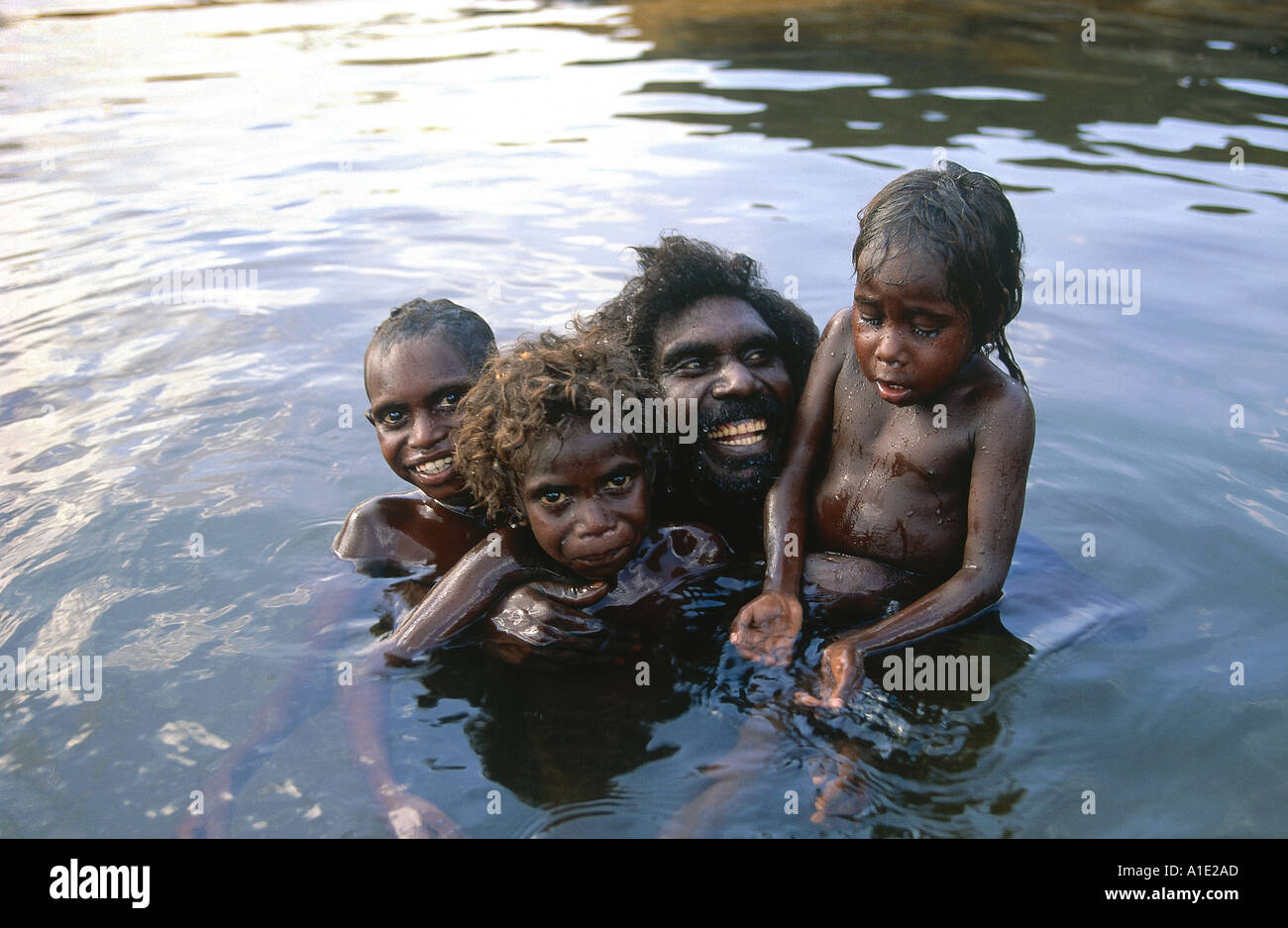 Anziano aborigeno Billy Nalakandi con i suoi figli Rayhab Romeo e Susannah cool-off e gioca in Kubumi billabong di Arnhem Land Foto Stock