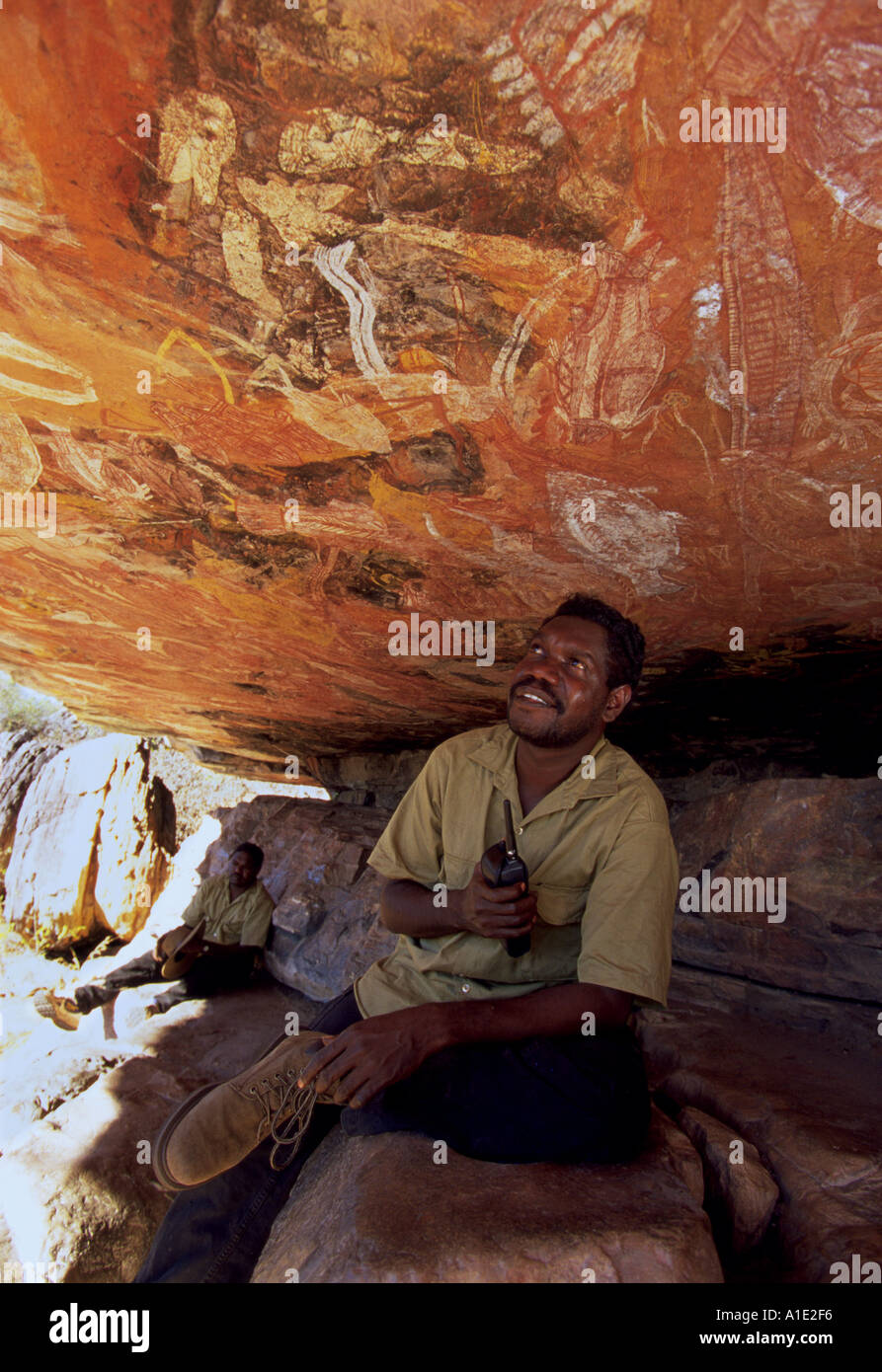 Aboriginal operaio Gabriel Maralngurra Isaia Magurrgurrba sondaggi antica arte rock pittura in grotta presso Injalak Foto Stock