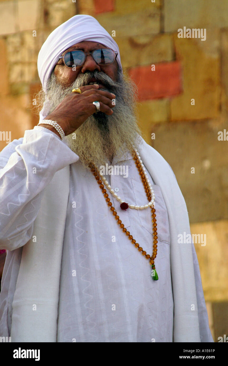 Il Guru sikh nel tradizionale abito bianco con perle e riflessa Qutb Minar in occhiali da sole stupiti della sua altezza Foto Stock
