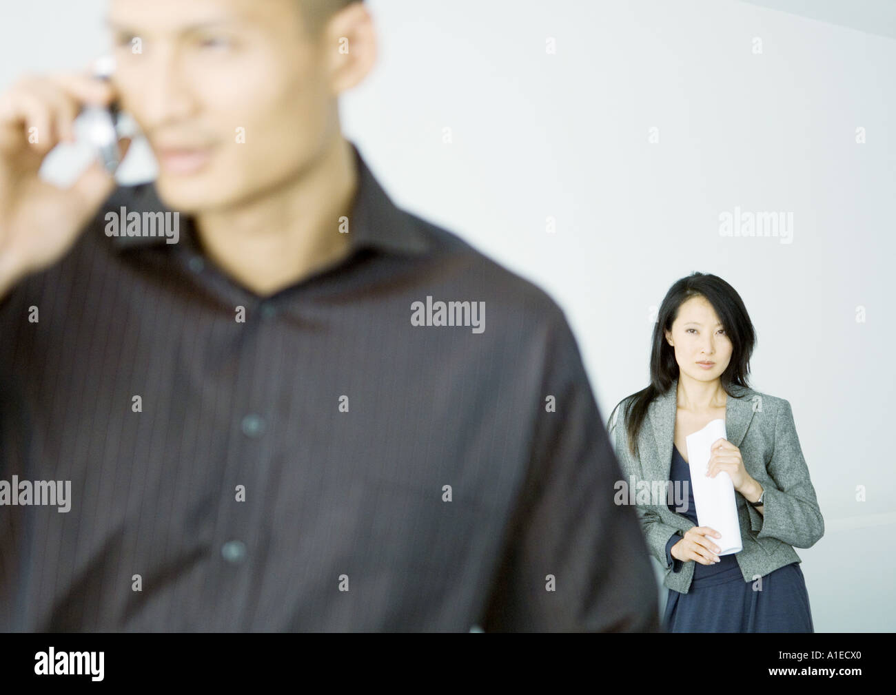Imprenditrice in piedi dietro l'uomo parlando al cellulare Foto Stock