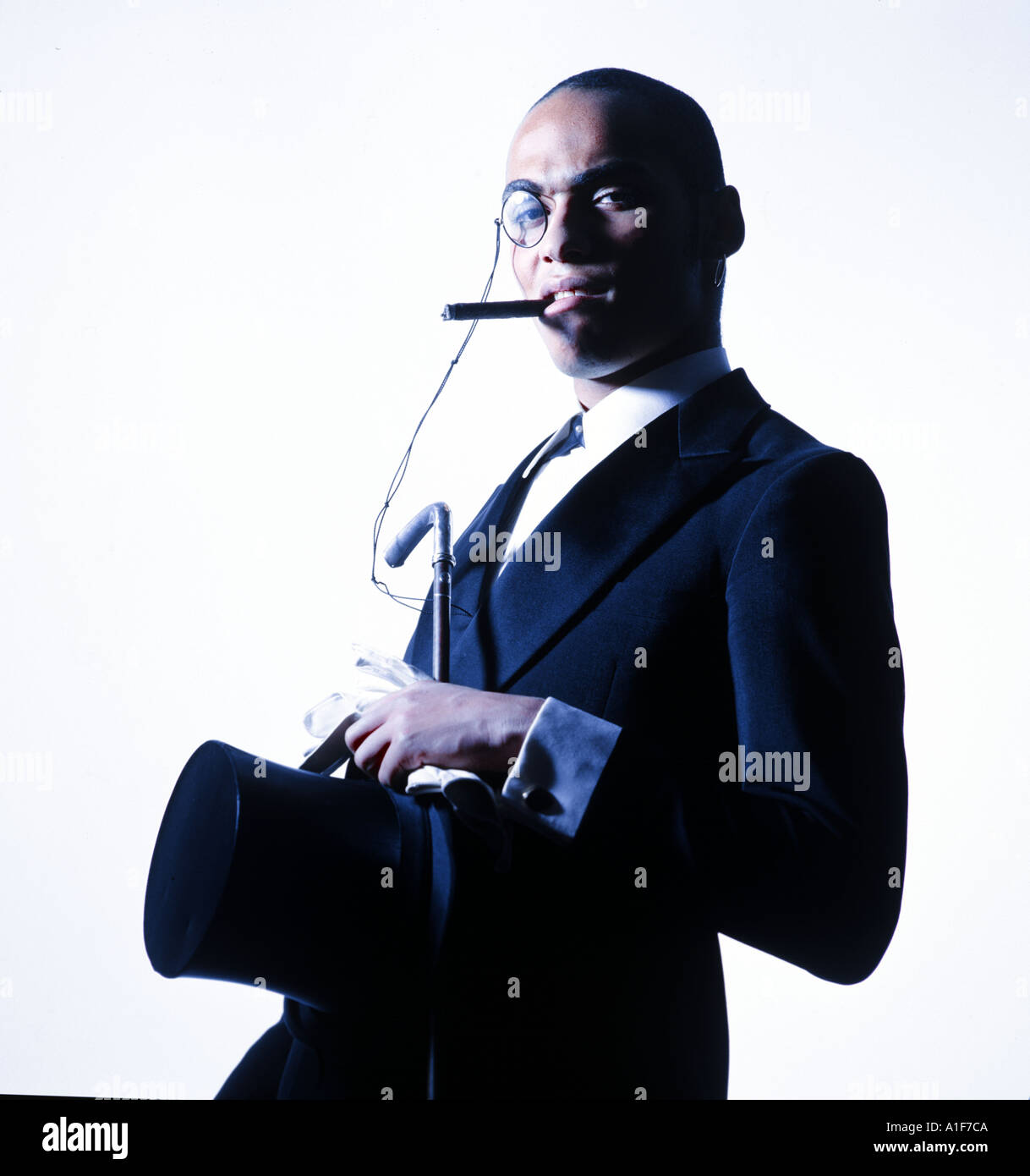 Giovane uomo nero con monoclasse sigaro e tailcoat outfit guardando molto sicuro di sé nella telecamera Foto Stock