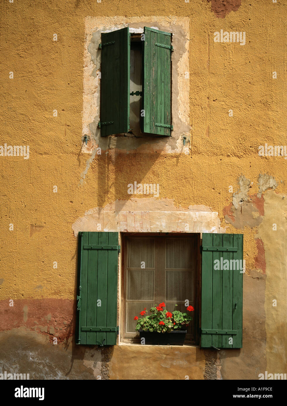 Persiane verdi su rustico ocra dipinto casa in Roussillon, provenza, Francia Foto Stock