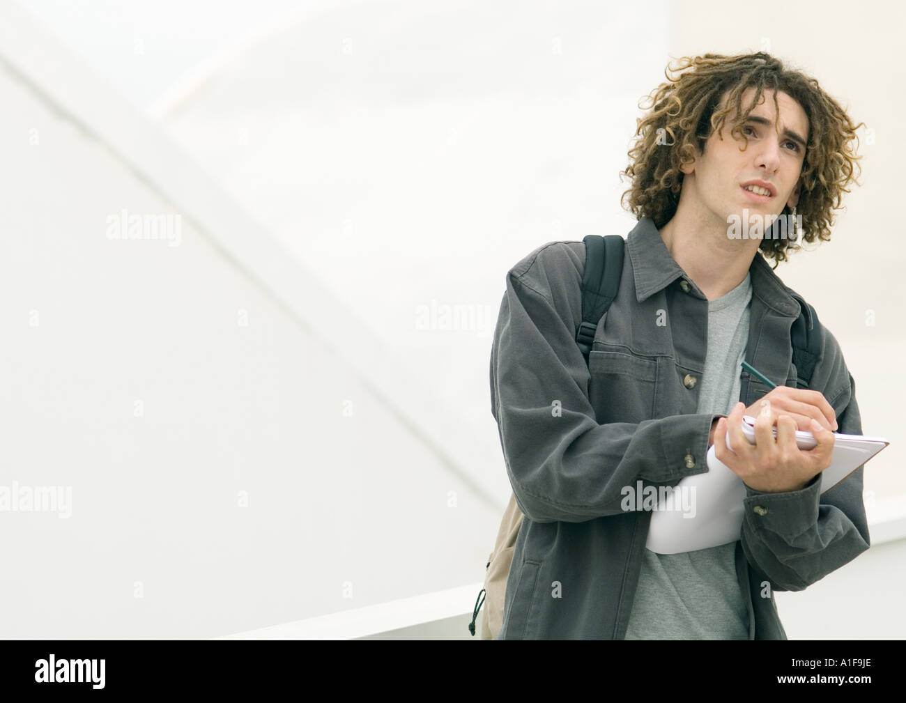 Giovane uomo in piedi con i notebook, prendere appunti Foto Stock