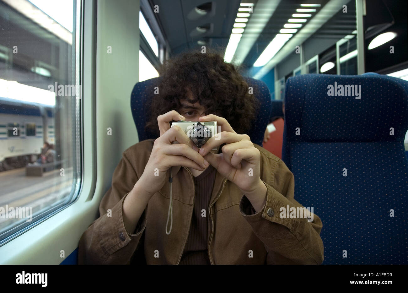 Giovane passeggero scatta foto con una piccola fotocamera digitale in una cabina ferroviaria Roma Italia Foto Stock