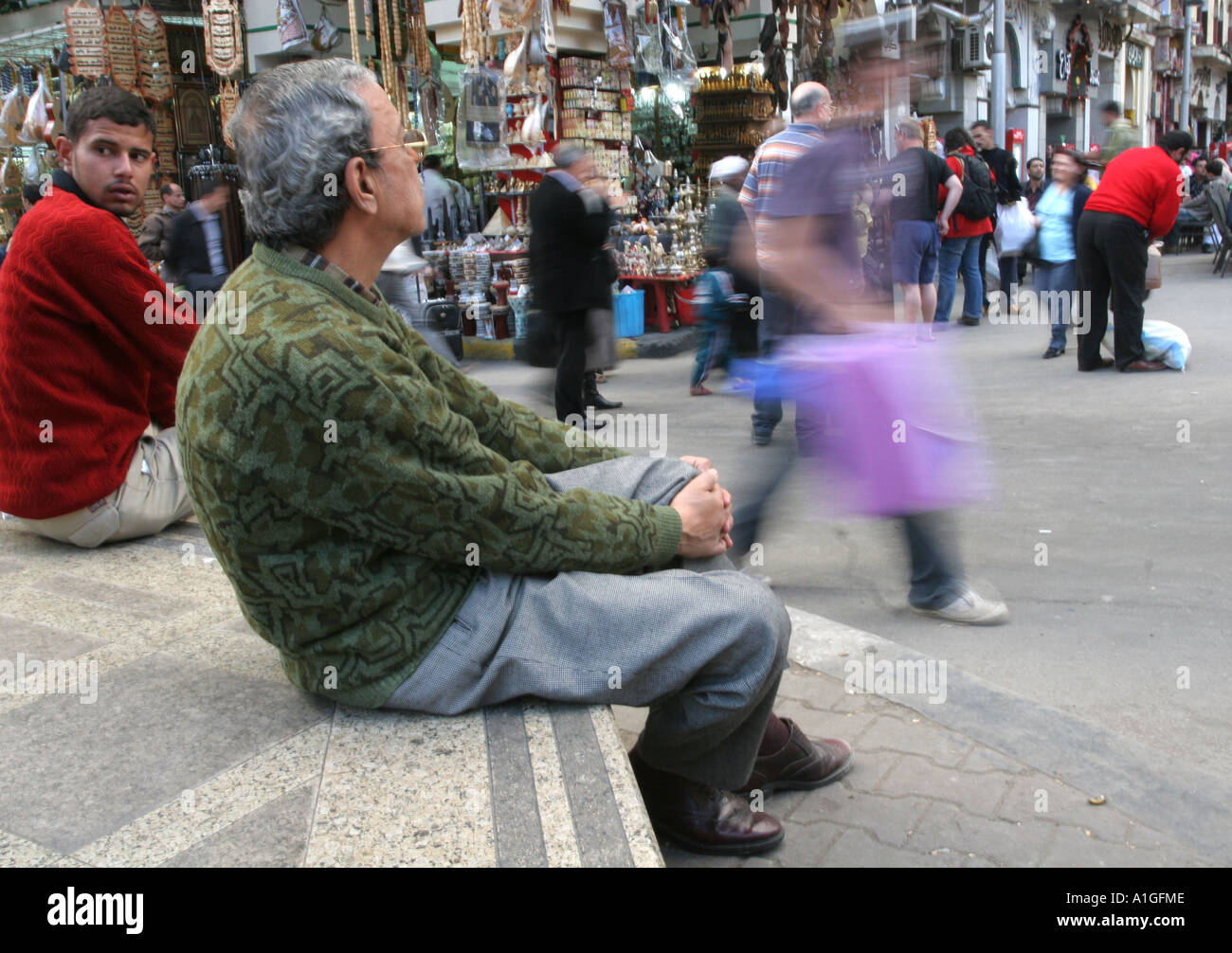 Un uomo si siede e guarda la vita scorrere nella trafficata Khan al Khalili al Cairo, Egitto Foto Stock