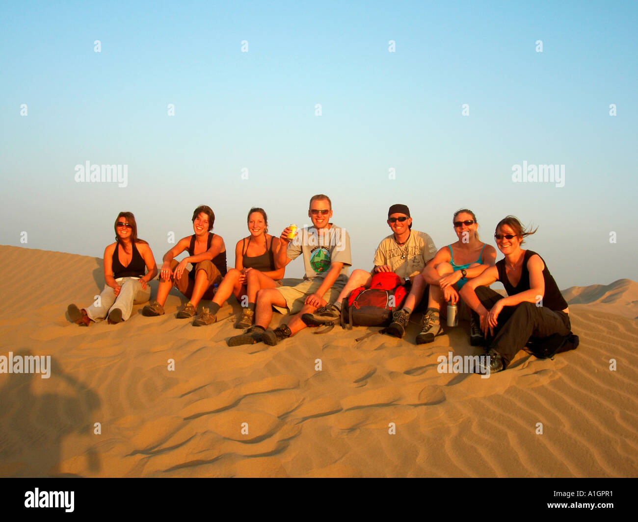 Gruppo di giovani in posa per una fotografia nelle dune sabbiose del deserto peruviano. Foto Stock
