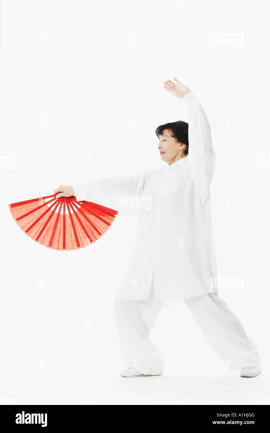 Donna matura ballare tenendo un ombrellone Foto Stock