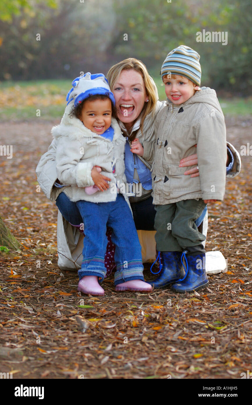 Una famiglia moderna madre e figlio e figlia divertirsi insieme in un parco verdeggiante. Foto Stock