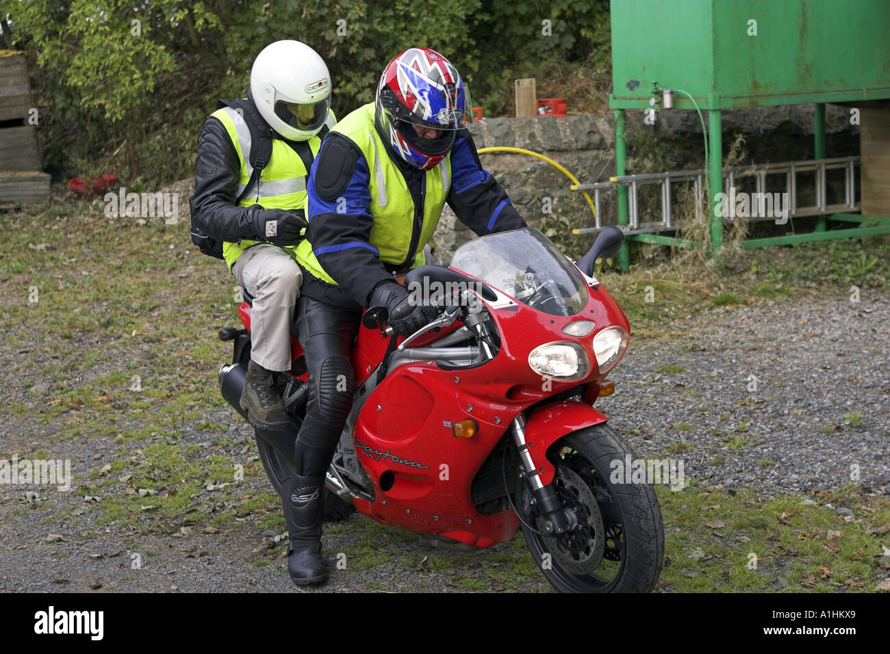 Due senior bikers su un rosso Triumph Daytona 955 moto indossa giacche ad alta visibilità e caschi Foto Stock