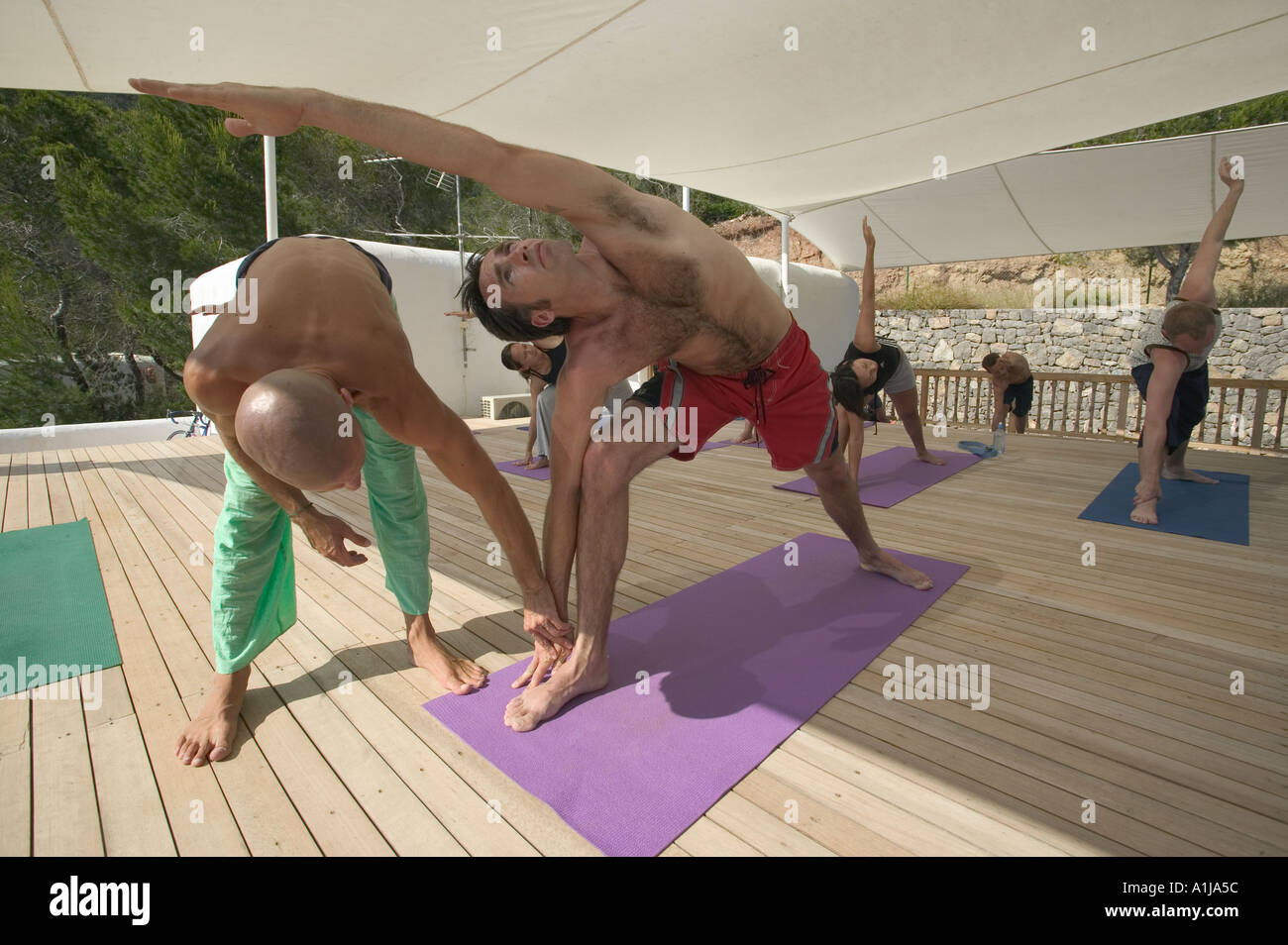 I villeggianti prendere tempo fuori con un tetto corso di yoga Yoga a Ibiza affacciato sulla Spiaggia Benirras in Ibiza in Spagna Europa Foto Stock