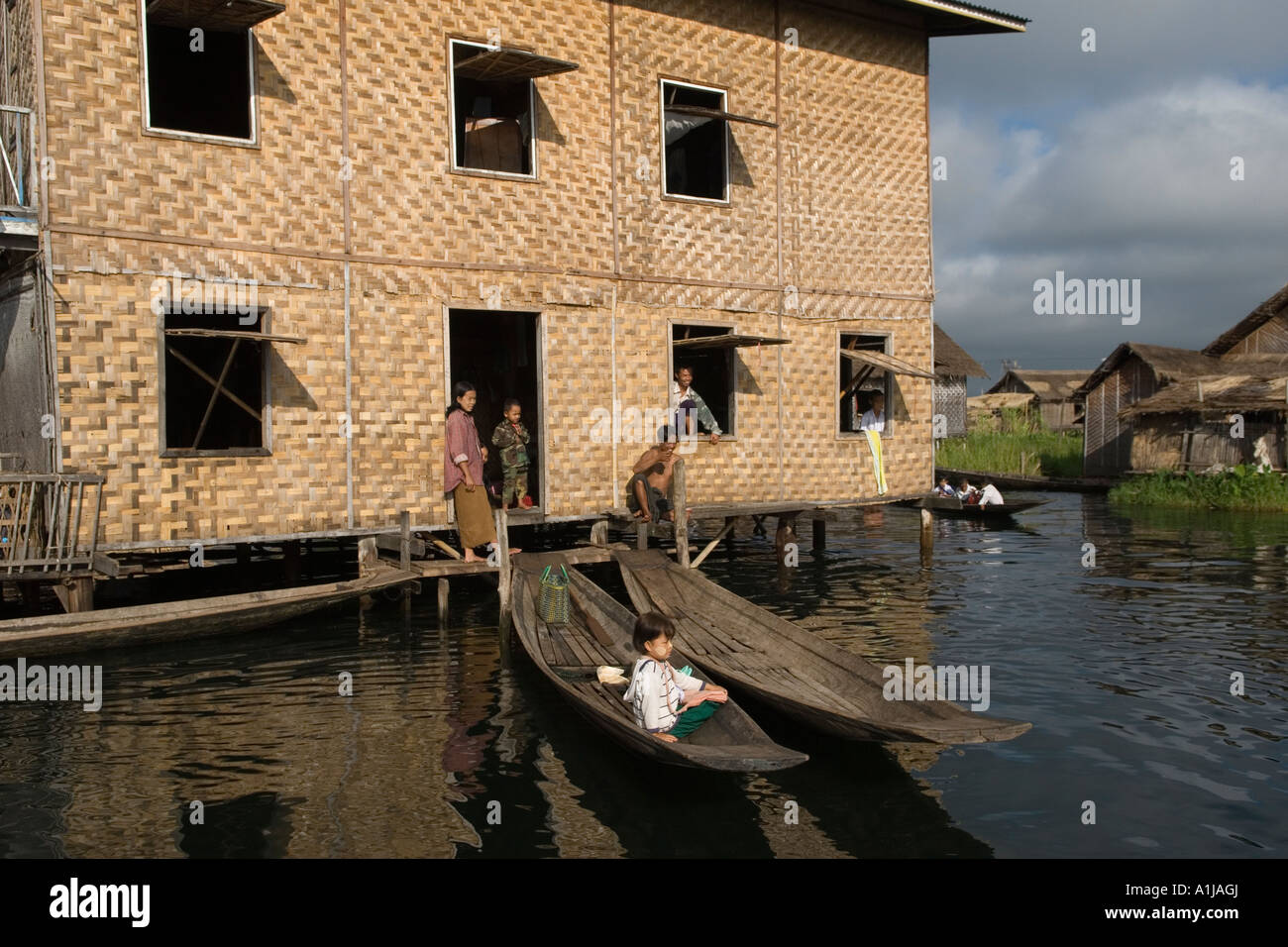 Casa costruita su palafitte, in legno ma rivestita in rattan, Inle Lake Myanmar Birmania, bambini in barca che chiacchierano. Stato Shan 2006 HOMER SYKES Foto Stock