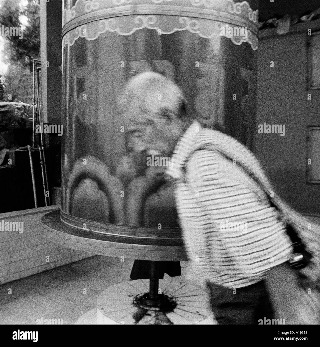 Tibetian uomo valking girando la grande ruota a pregare sulla strada del tempio in McLeod Ganj Kangra Valley Himachal Pradesh India Foto Stock