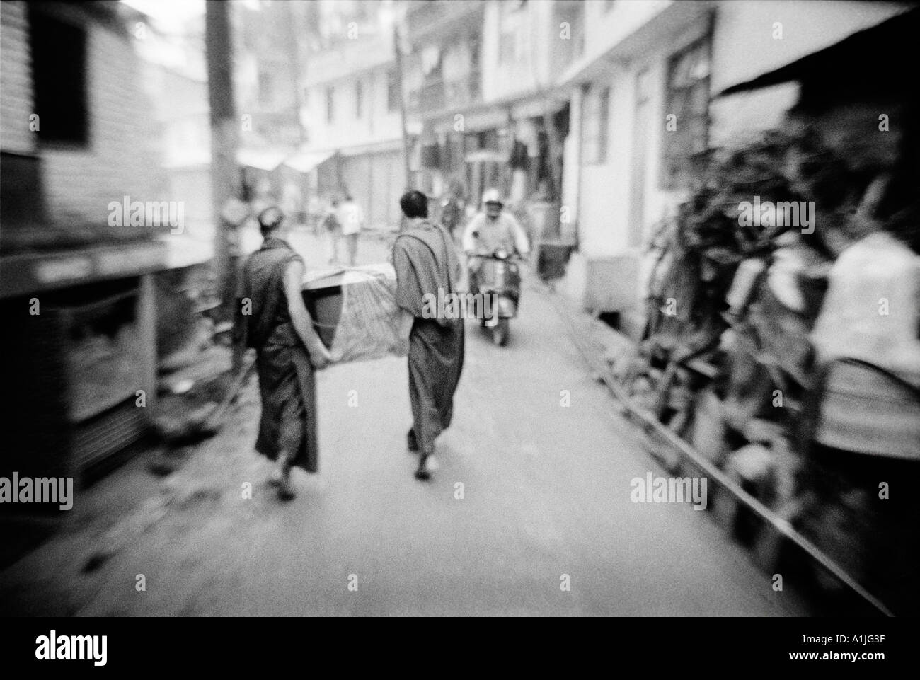 Due monaci tibetani in esecuzione con un TV sulla strada tra Bhagsu e McLeod Ganj Kangra Valley Himachal Pradesh India Foto Stock