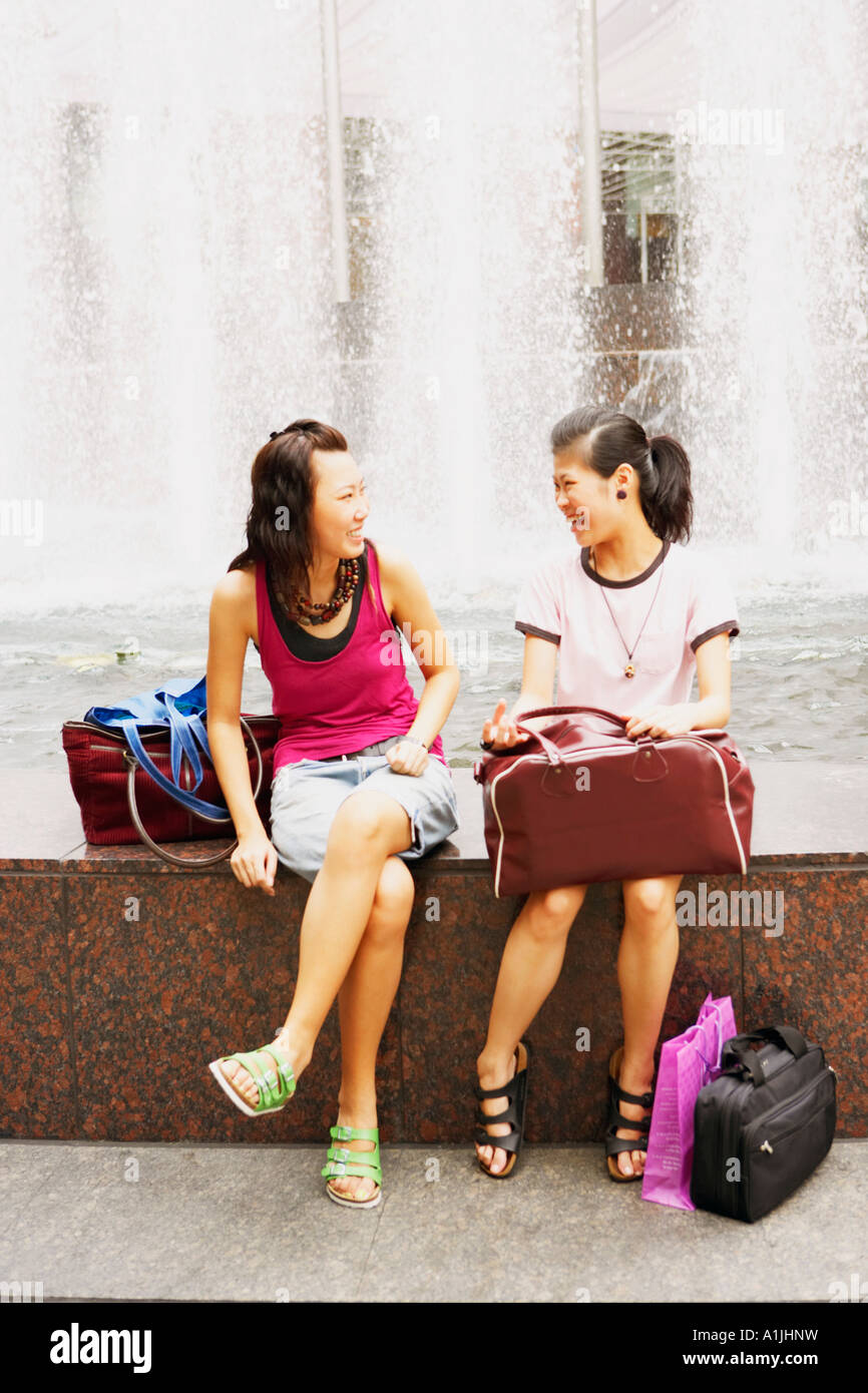 Due giovani donne parlando vicino a una fontana Foto Stock