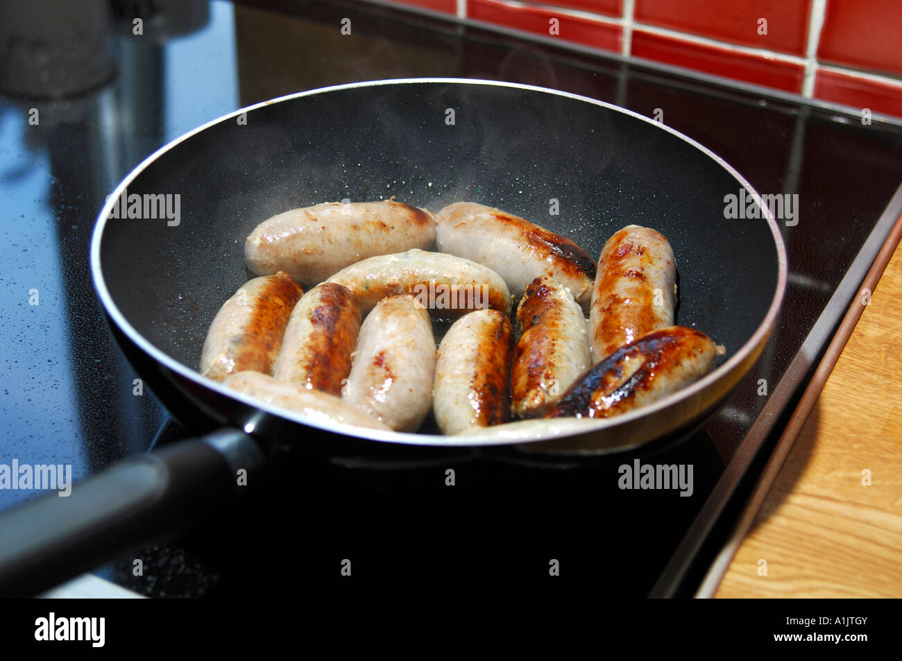 Spesso le salsicce di maiale per friggere in una padella Foto Stock