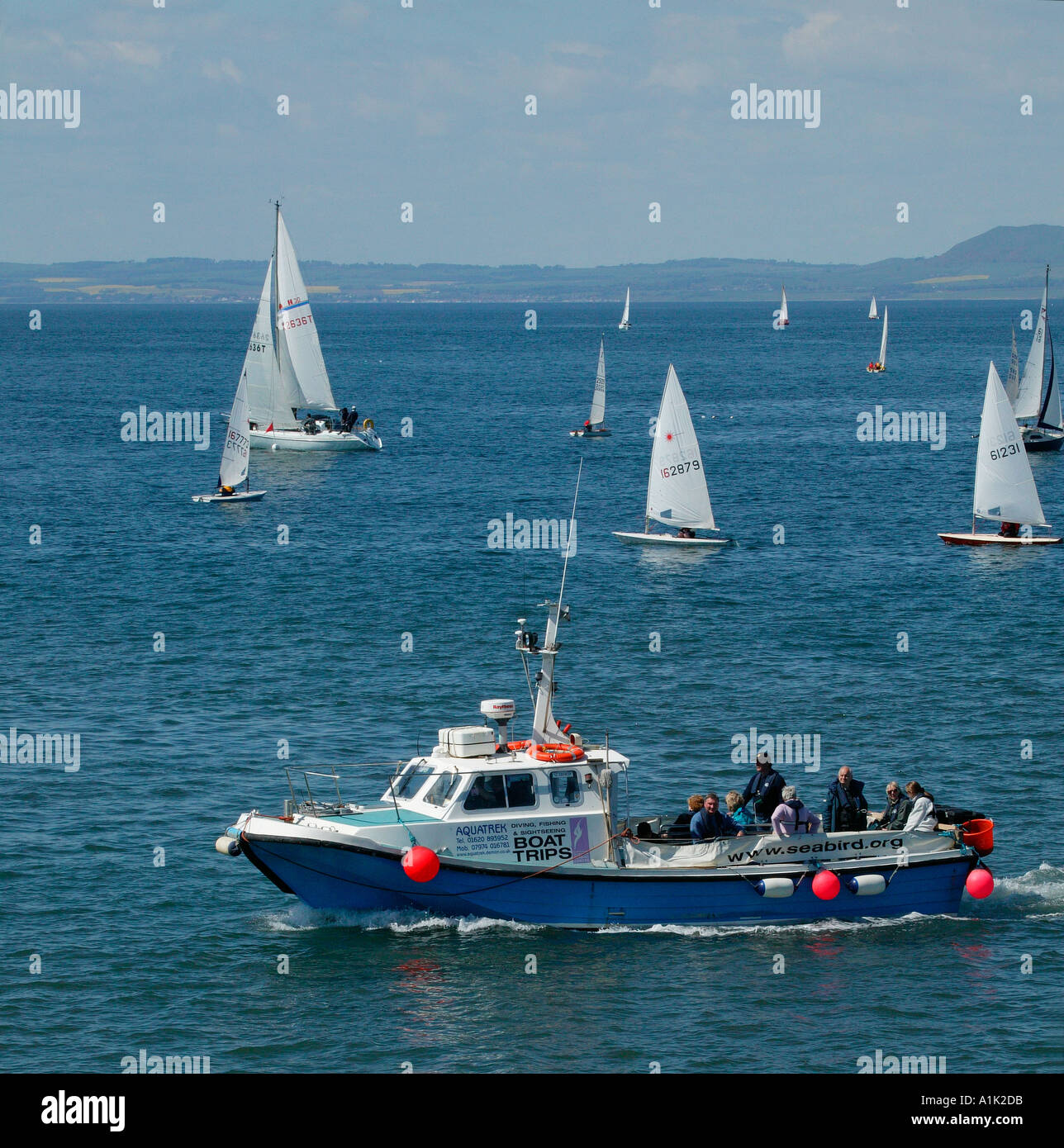 Barche a vela vela in background a North Berwick East Lothian in Scozia con tour in barca in primo piano Foto Stock