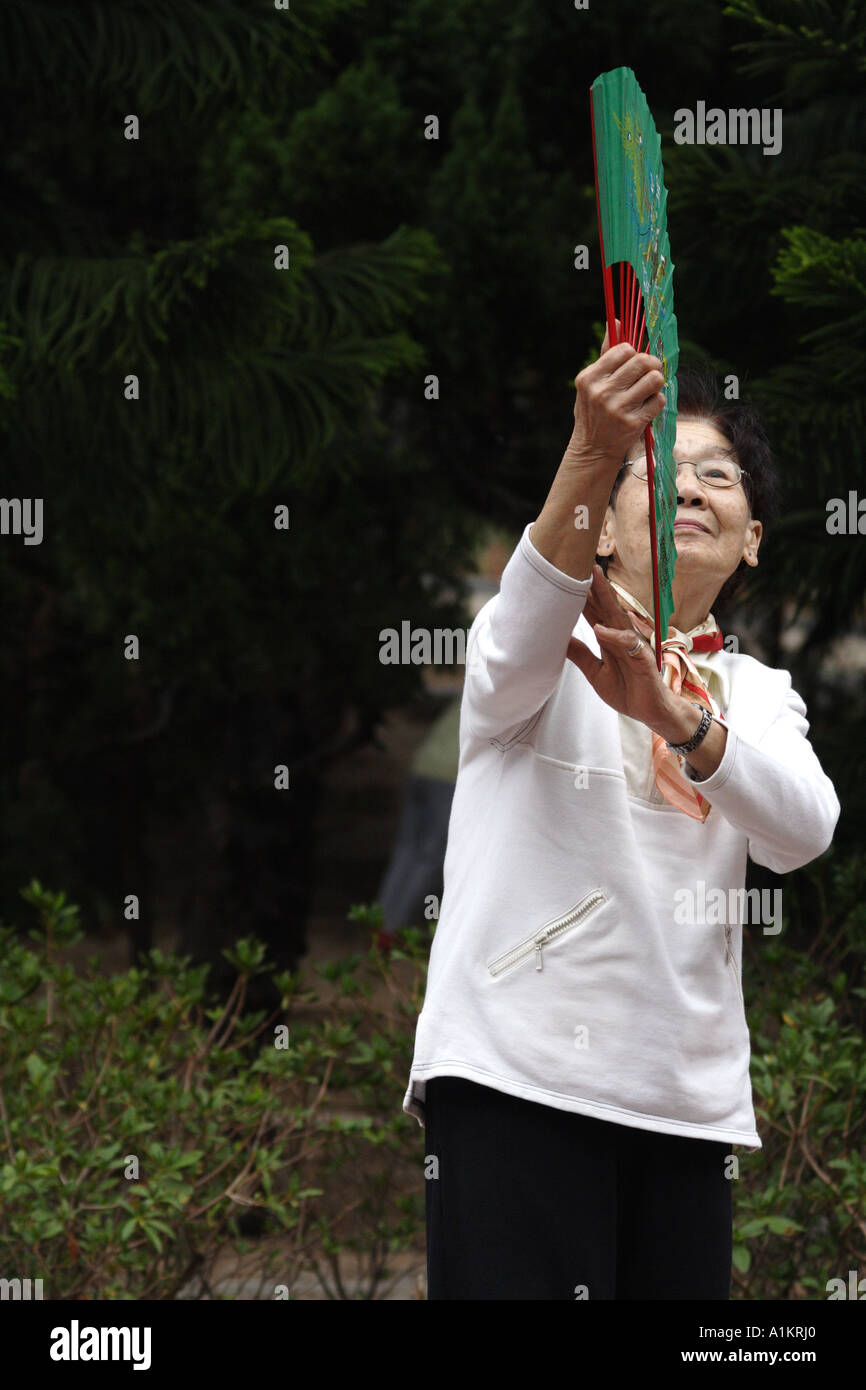 Le pratiche di donna Tai Chi con un ventilatore in Victoria Park, Hong Kong Foto Stock