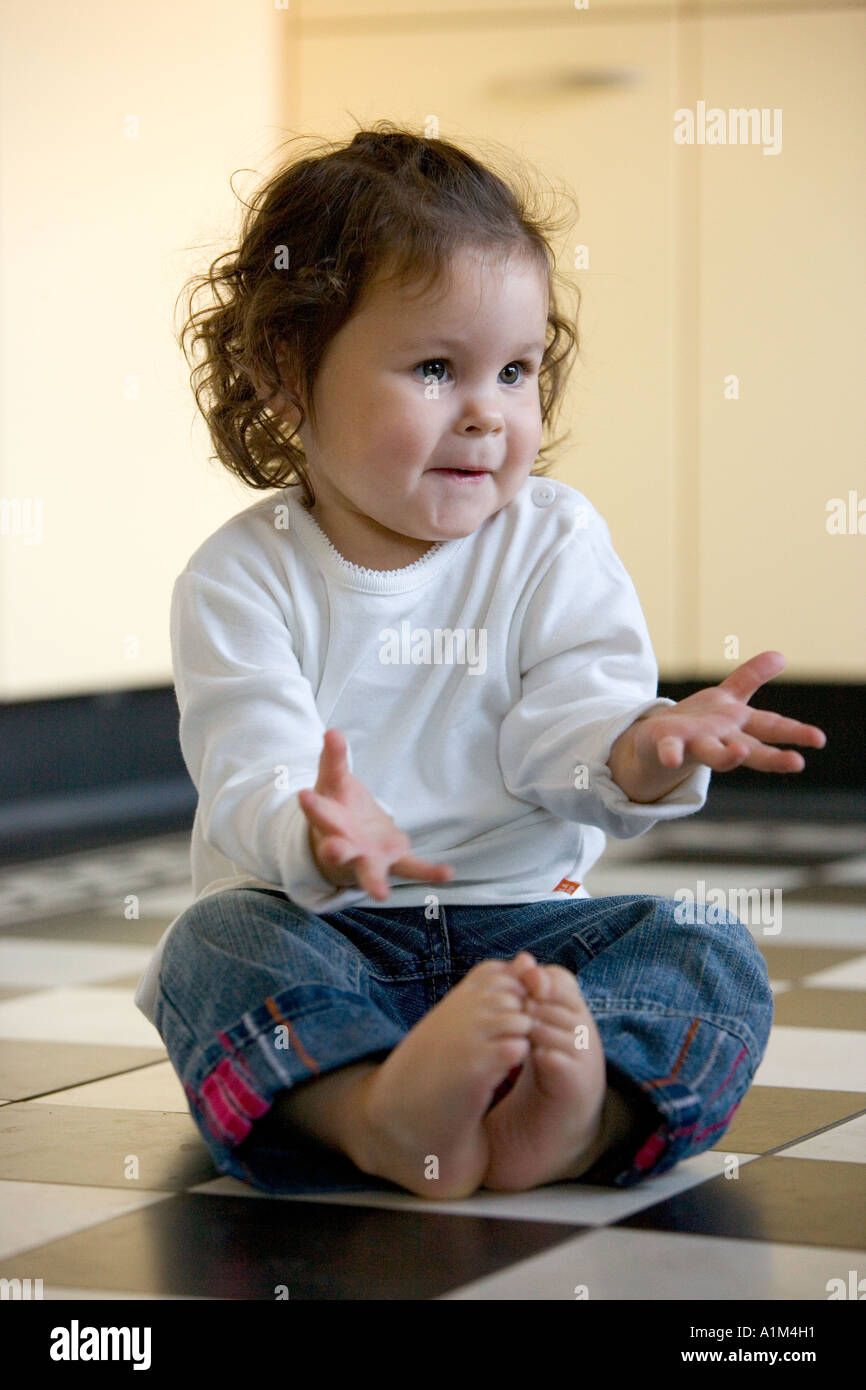 Bambino è seduto sul pavimento e gesticulate Foto Stock