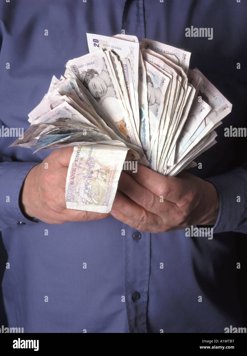 Primo piano uomo accatenamento e mano che afferra tenendo su pile di contanti assortiti in sterlina banconote da banca posto da modello studio foto Inghilterra Regno Unito Foto Stock