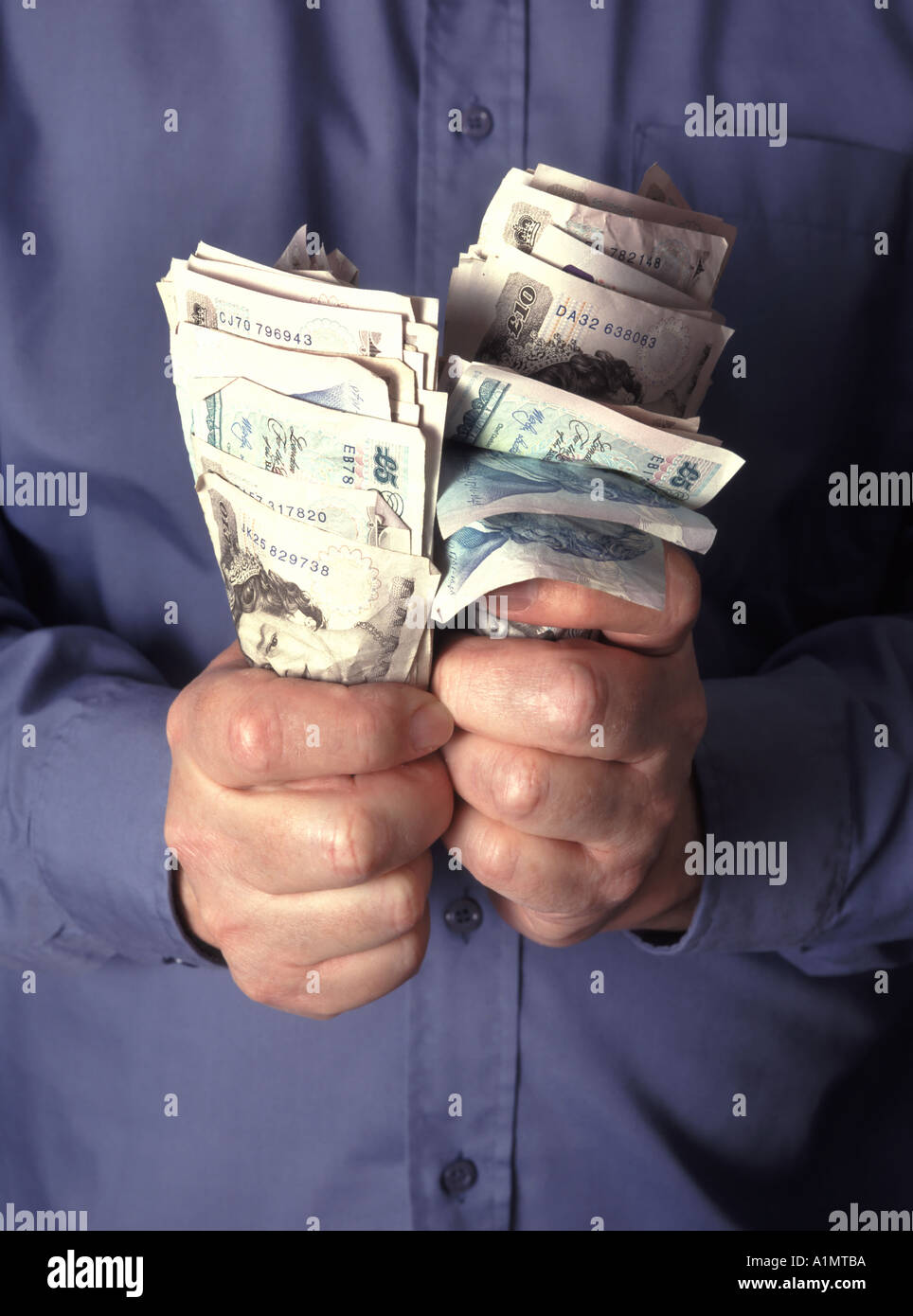 Business uomo clenched pugno che afferra e tenendo su pile di contanti assortiti in sterlina banconote in banca posti dal modello Inghilterra UK Foto Stock