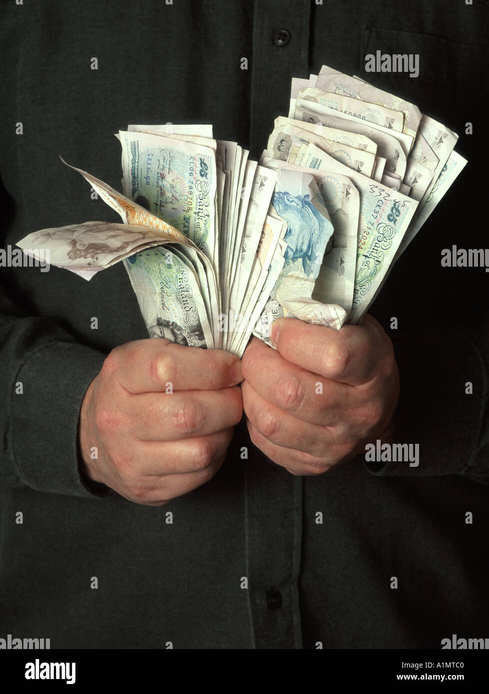 Primo piano uomo d'affari due mani afferrando l'accodamento & tenuta sulle pile di contanti assortiti in libbra sterlina banconote posto dal modello Inghilterra UK Foto Stock