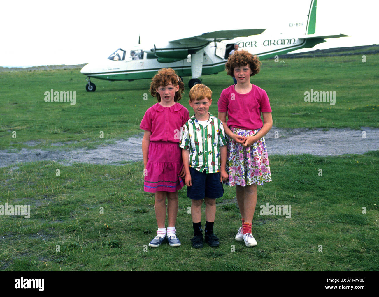 Testa rossa sorelle con il loro fratello più giovane di attendere per vedere TH aereo decollare da INISH (Fine) significa Isole Aran co Galway, Irlanda Foto Stock