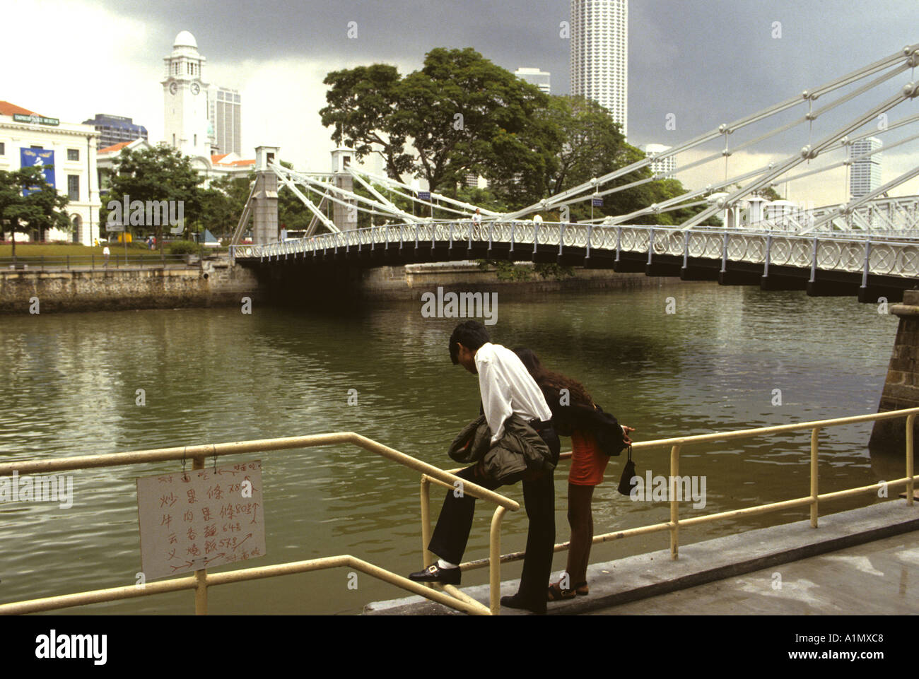 Coppia giovane lo sguardo al fiume da un ponte in Singapore Foto Stock