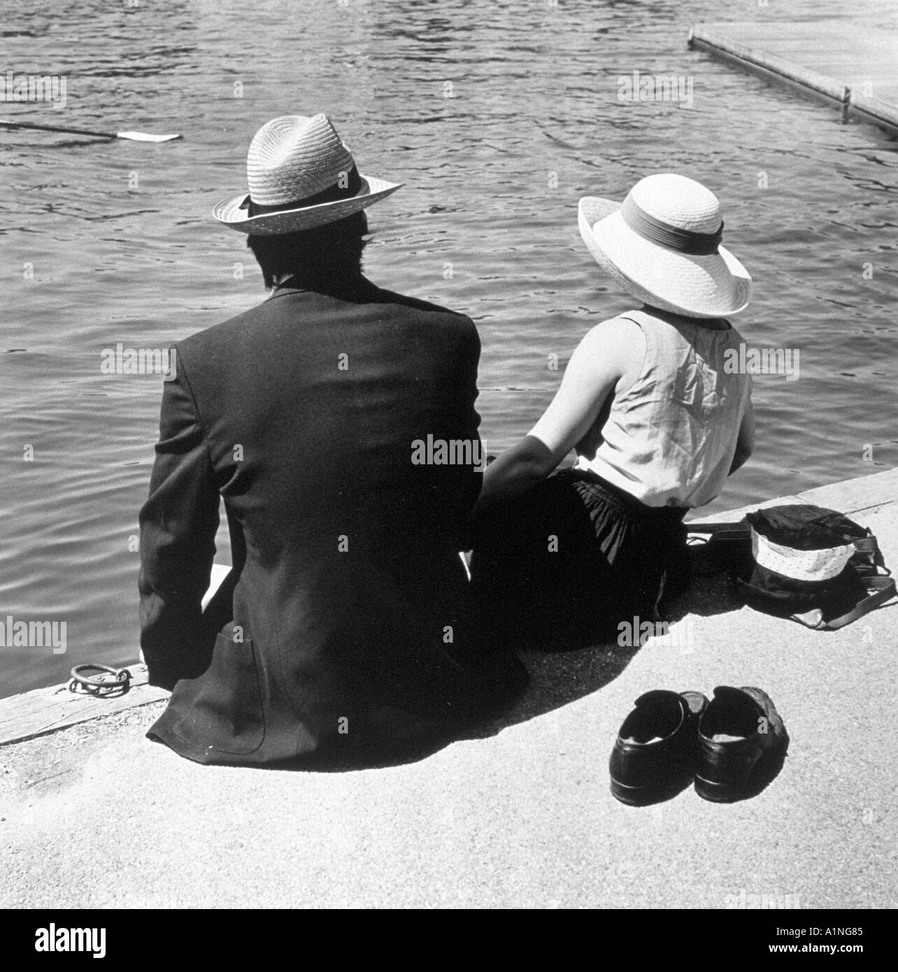 Giovane seduto con le scarpe OFF sulla banca del fiume a Henley Regatta Foto Stock