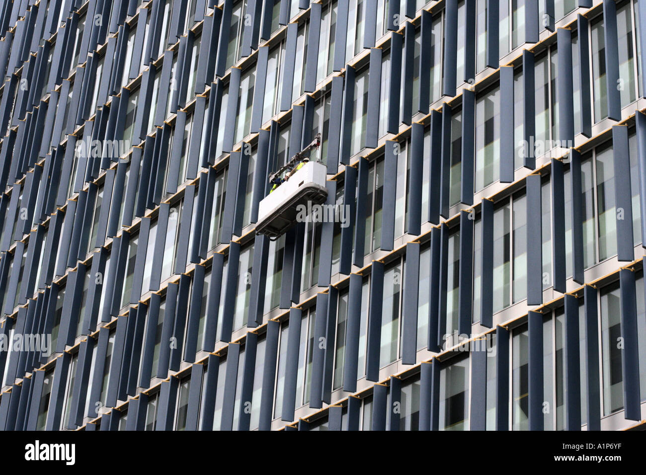 In gondola per la pulizia di vetri sospeso sulla parte anteriore dell'edificio Foto Stock
