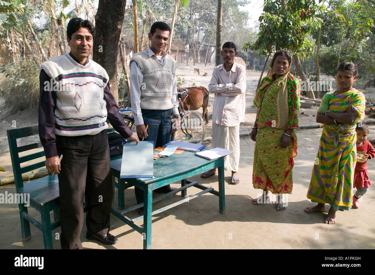Gli uomini la raccolta di denaro da donne che partecipano in un micro-credito programma di prestito nel nord del Bangladesh Foto Stock