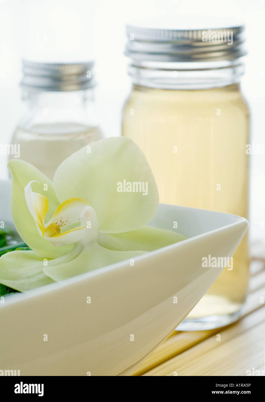 Fioritura di orchidee e bottiglie di oli essenziali Foto Stock
